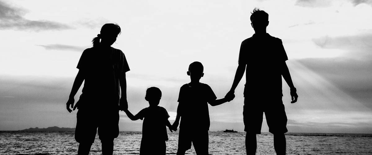 Silhouetted family holding hands at the beach