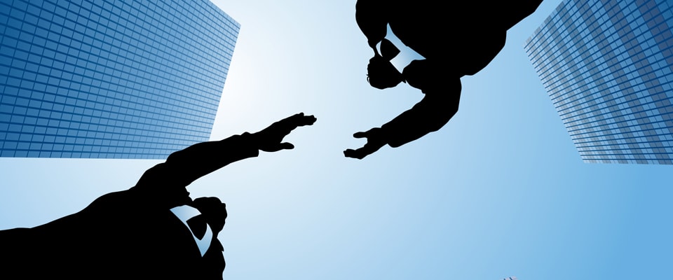 Two professionals reaching toward each other against city skyline